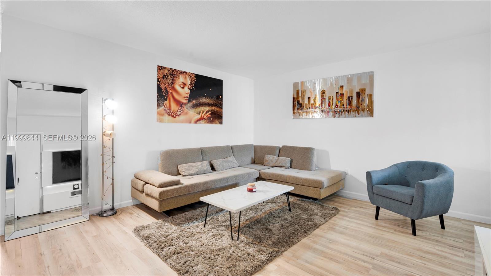 A living room features a grey sectional sofa, a coffee table, and a blue armchair — 16900 NE 14th Ave # 204, Miami FL 33162, MIAMI, FL