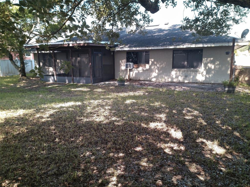 The backyard of a single-story house features a screened-in porch and a grassy lawn — 2419 AMBERLY AVENUE, ORLANDO, FL