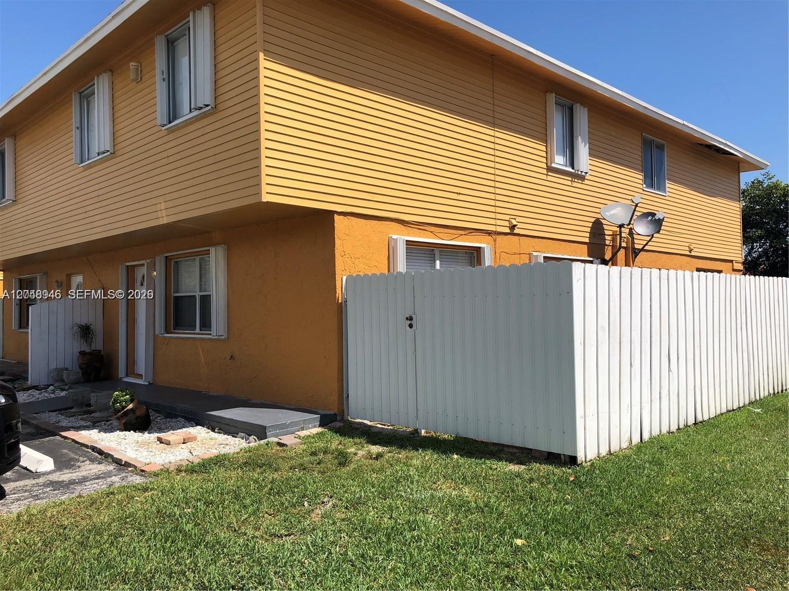 A two-story yellow building with a white fence and a small front patio area — 43 NE 12th Ave # 43, Homestead FL 33030, HOMESTEAD, FL