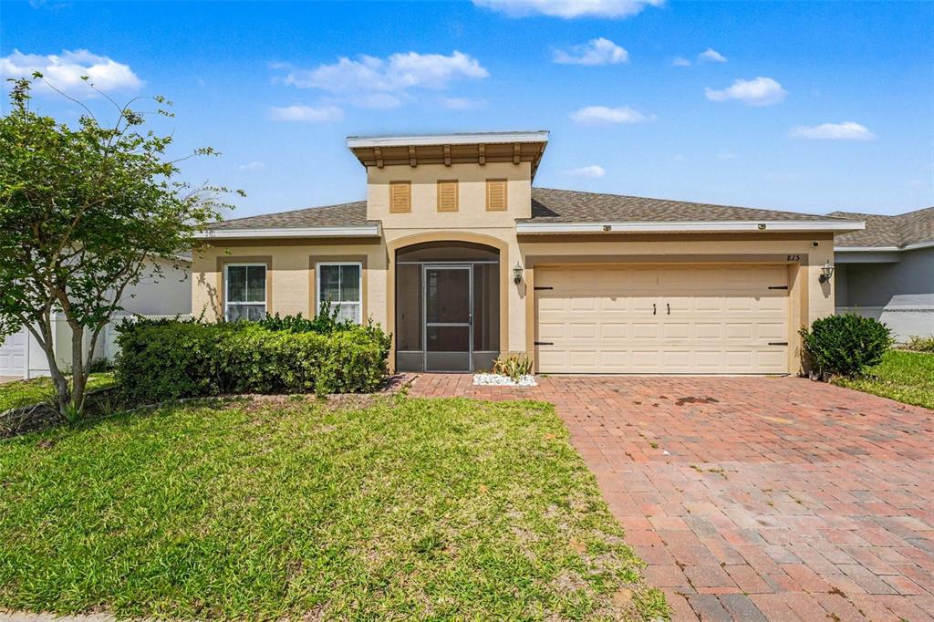 A single-story house with a tan stucco exterior, a screened entryway, and a brick driveway — 815 MONTGOMERY WAY, DAVENPORT, FL