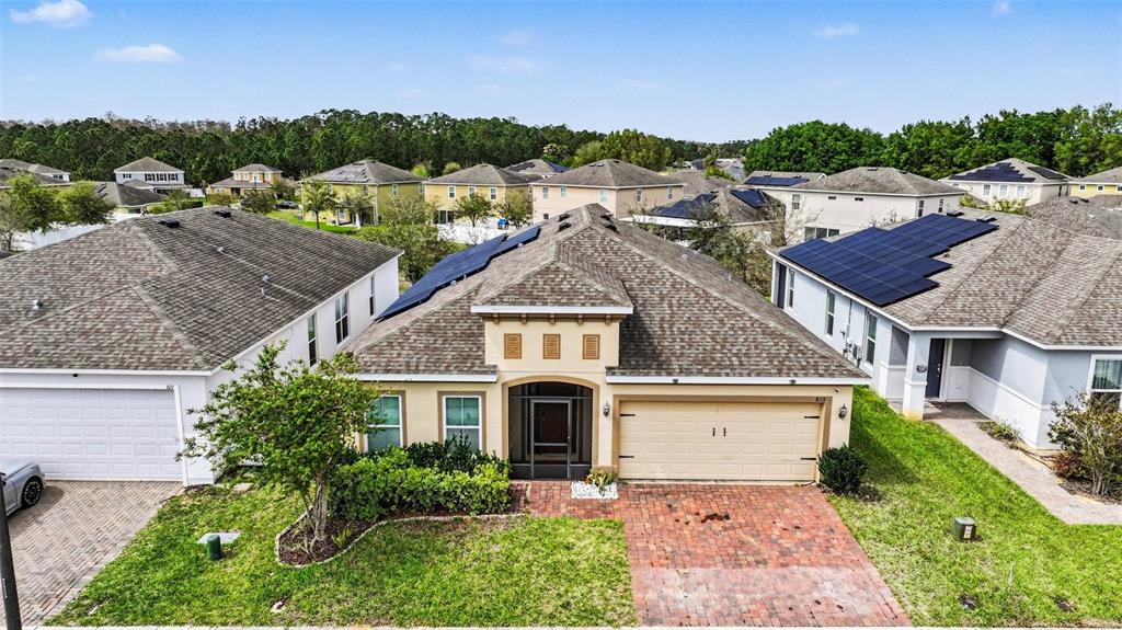 An aerial view of a suburban house with a brick driveway and solar panels — 815 MONTGOMERY WAY, DAVENPORT, FL