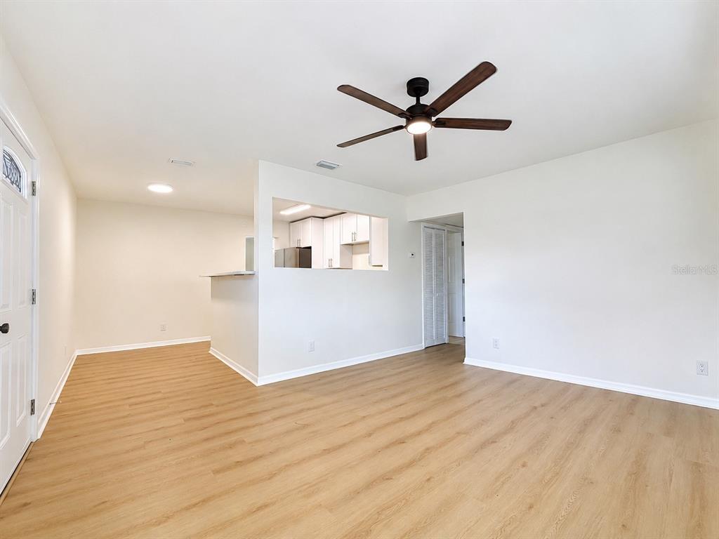 An empty living room with light wood-look flooring, white walls, and a ceiling fan — 4112 OHIO AVENUE, TAMPA, FL