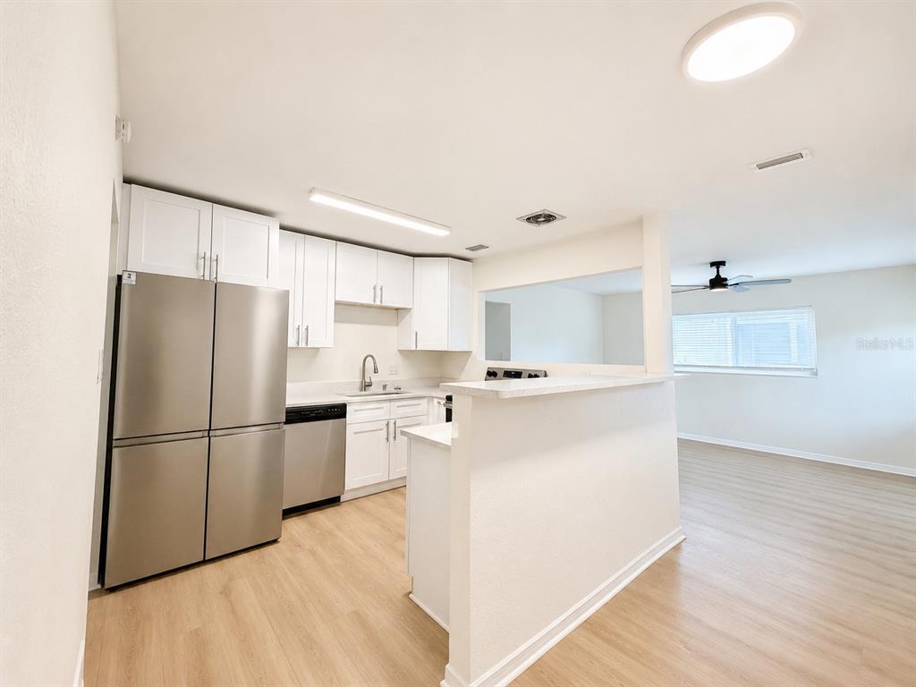 A kitchen with white cabinets, stainless steel appliances, and light wood-look flooring — 4112 OHIO AVENUE, TAMPA, FL