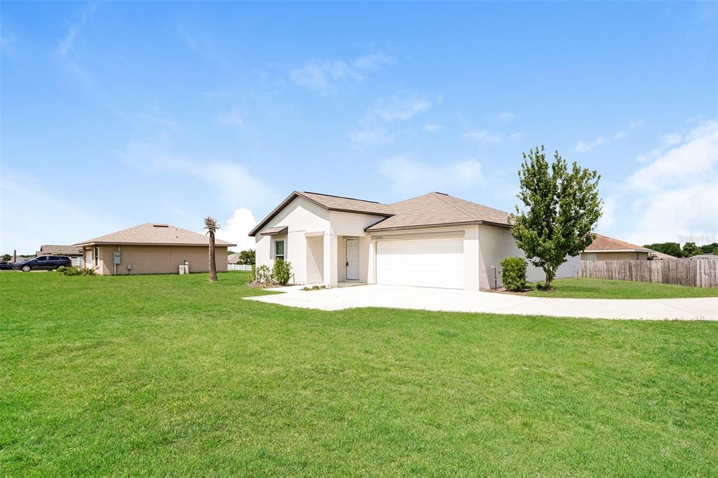 A single-story house with a beige exterior, a two-car garage, and a large front lawn — 12495 SE 100TH AVENUE, BELLEVIEW, FL