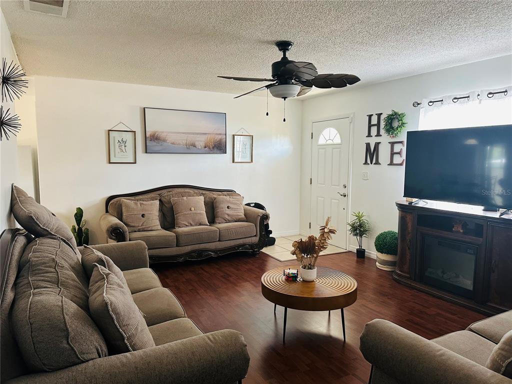 A living room features brown sofas, a round coffee table, and a television on a stand — 640 E CUMMINGS STREET, LAKE ALFRED, FL