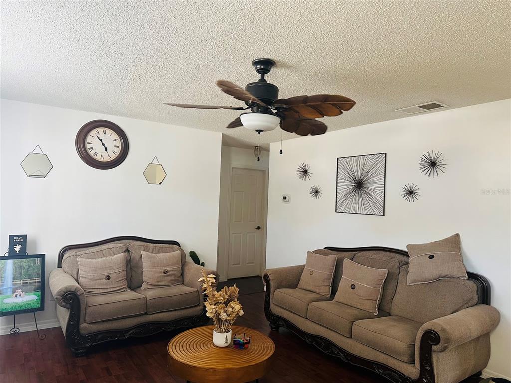A living room features two brown sofas, a round wooden coffee table, and a ceiling fan — 640 E CUMMINGS STREET, LAKE ALFRED, FL