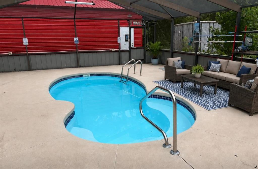 A kidney-shaped swimming pool sits on a concrete patio enclosed by a screened lanai — 12253 E BERRY LANE, FLORAL CITY, FL