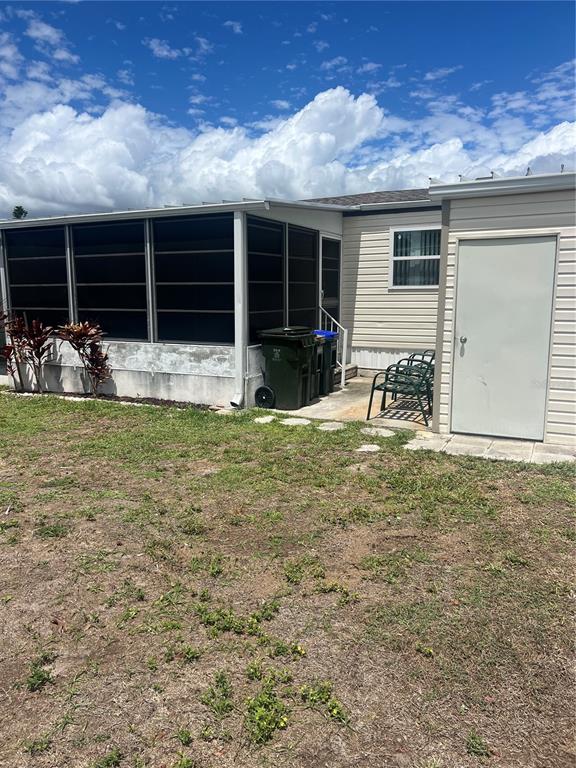 The exterior of a mobile home features a screened-in porch, a storage shed, and trash bins — 6420 HAELE COURT, NORTH PORT, FL