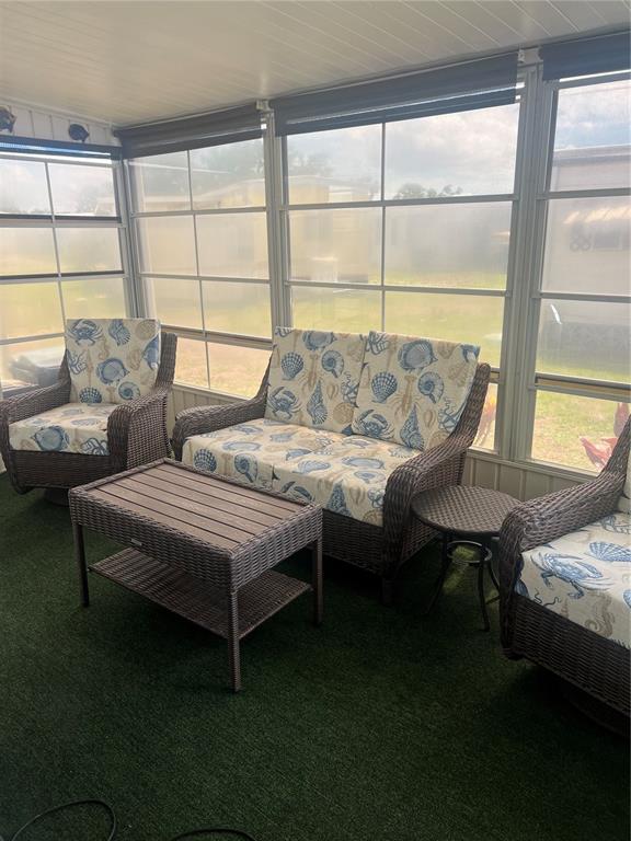 A sunroom features wicker furniture with seashell-patterned cushions on a green artificial turf floor — 6420 HAELE COURT, NORTH PORT, FL