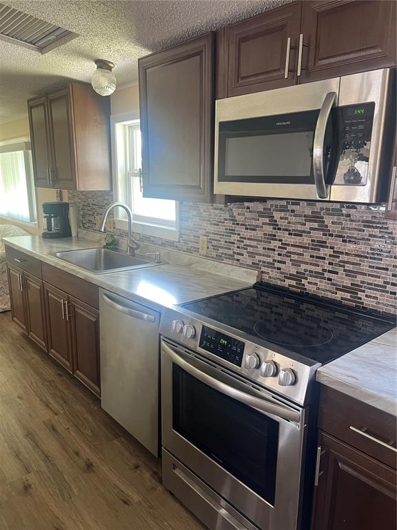 A kitchen features dark wood cabinets, stainless steel appliances, and a mosaic tile backsplash — 6420 HAELE COURT, NORTH PORT, FL