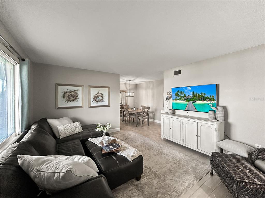 A living room features a dark leather sectional, a white media console, and a dining area — 1600 W LAKE PARKER DRIVE UNIT C4, LAKELAND, FL