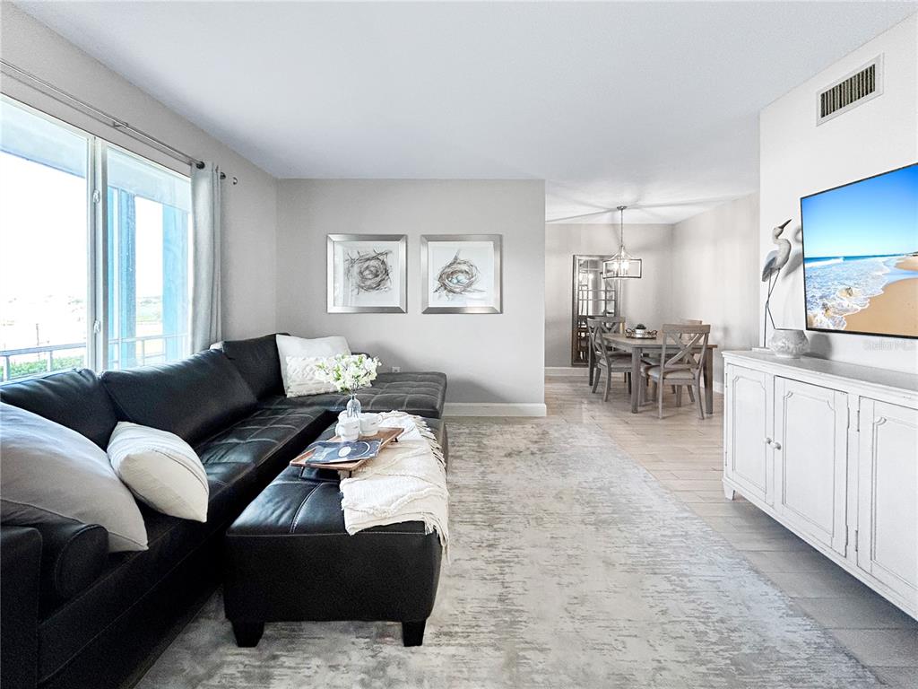 A living room features a black sectional sofa, a white media console, and a dining area — 1600 W LAKE PARKER DRIVE UNIT C4, LAKELAND, FL