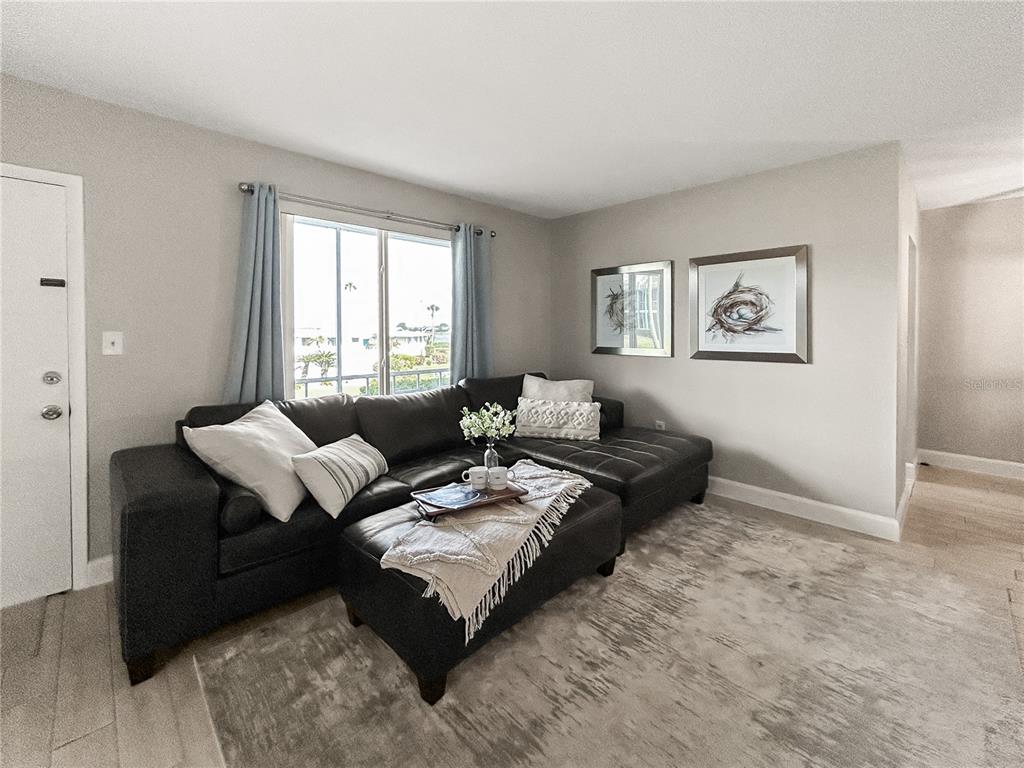 A living room features a dark sectional sofa, a matching ottoman, and two framed wall prints — 1600 W LAKE PARKER DRIVE UNIT C4, LAKELAND, FL