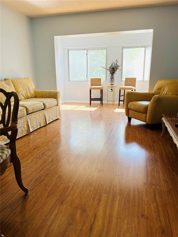 A living room features light blue walls, wood-look flooring, a yellow sofa, and an armchair — 8651 10TH STREET N UNIT 210, ST PETERSBURG, FL