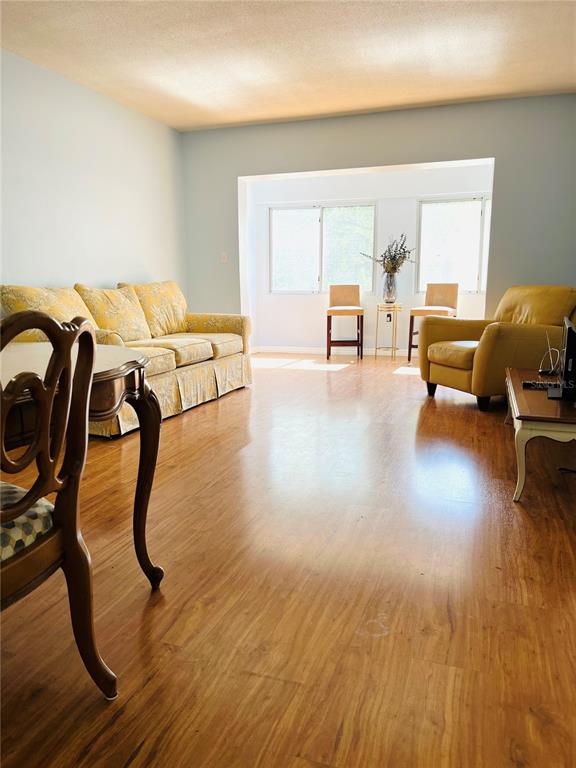A living room features light blue walls, wood flooring, a yellow sofa, and a yellow armchair — 8651 10TH STREET N UNIT 210, ST PETERSBURG, FL