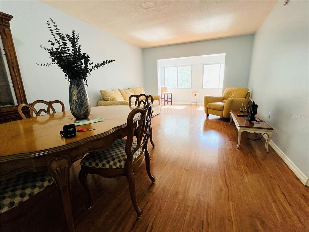 A dining area with a wooden table leads into a living room with yellow furniture — 8651 10TH STREET N UNIT 210, ST PETERSBURG, FL