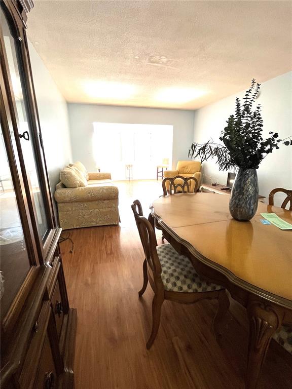 A dining area with a wooden table and chairs leads into a living room — 8651 10TH STREET N UNIT 210, ST PETERSBURG, FL