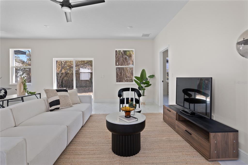A modern living room features a white sectional sofa, a round coffee table, and a television — 1531 OAK LANE, CASSELBERRY, FL