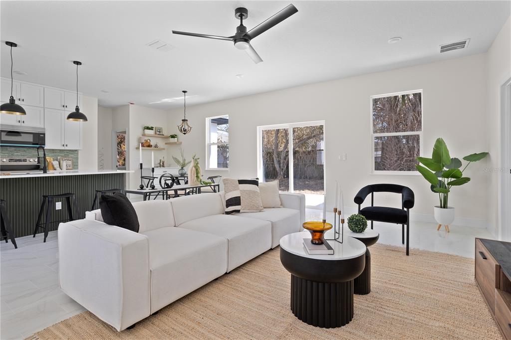 A modern open-concept living room and kitchen featuring a white sofa, coffee tables, and ceiling fan — 1531 OAK LANE, CASSELBERRY, FL
