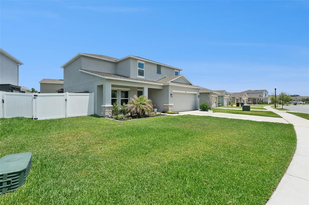 A two-story suburban house with a gray exterior, a two-car garage, and a white fence — 584 PINK IBIS BEND, ST CLOUD, FL