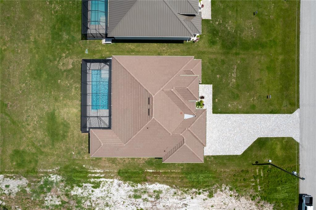 An aerial view shows a house with a tiled roof, a screened pool, and a driveway — 241 ROTONDA BOULEVARD S, ROTONDA WEST, FL