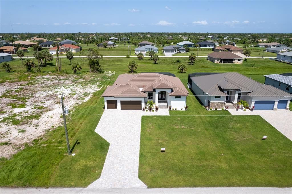 An aerial view shows a single-story house with a tiled roof and a paved driveway — 241 ROTONDA BOULEVARD S, ROTONDA WEST, FL