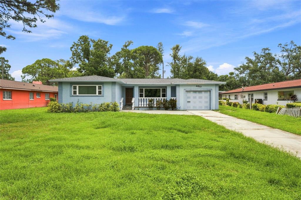 A light blue single-story house with a front lawn, attached garage, and concrete driveway — 4310 DR MARTIN LUTHER KING JR STREET S, ST PETERSBURG, FL