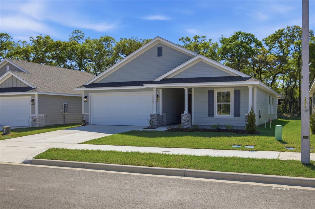 A single-story house with light blue siding, a two-car garage, and a stone-accented front porch — 16822 NW 178TH TERRACE, ALACHUA, FL