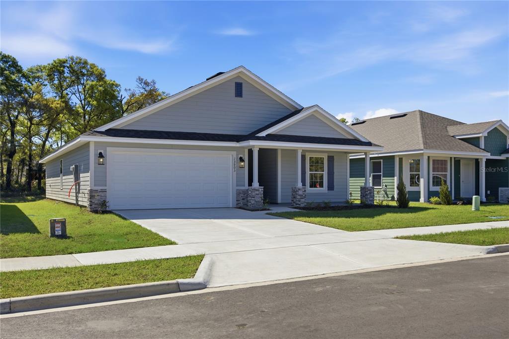 A light blue single-story house with a two-car garage and a covered front porch — 16822 NW 178TH TERRACE, ALACHUA, FL
