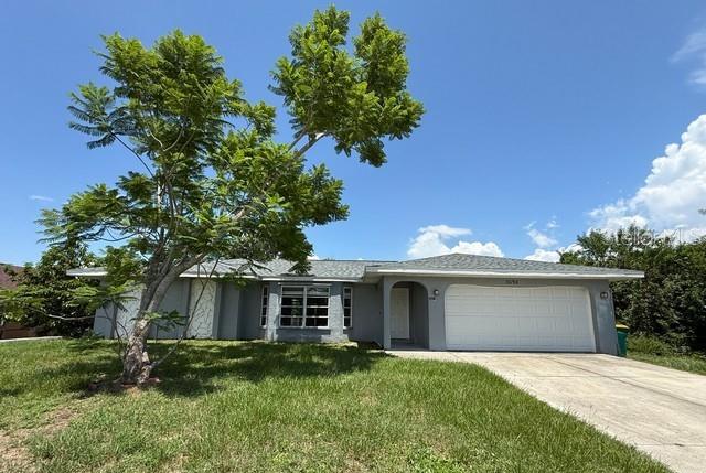 A single-story house with a white garage door and a large tree in the yard — 3098 BEACON DRIVE, PORT CHARLOTTE, FL