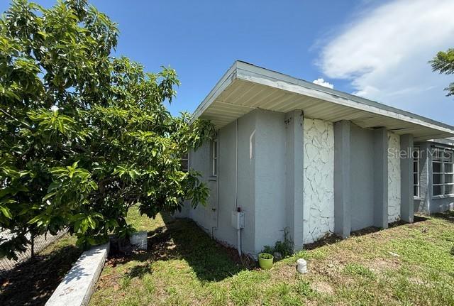A side view of a gray house with stone accents and a large green tree — 3098 BEACON DRIVE, PORT CHARLOTTE, FL