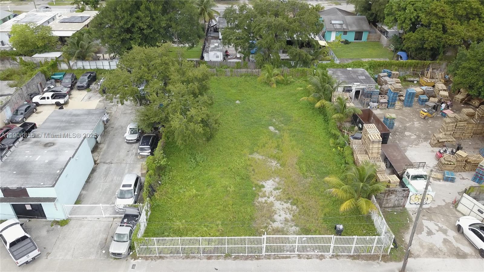 An aerial view shows a rectangular vacant lot bordered by a white fence and buildings — 3039 NW 54th St, Miami FL 33142, MIAMI, FL