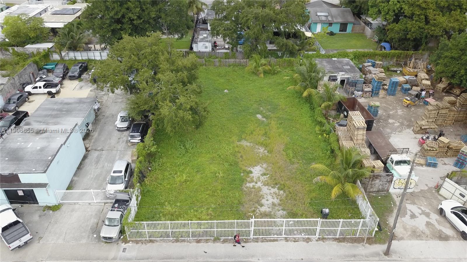 An aerial view shows a vacant, fenced-in rectangular lot situated between two commercial properties — 3039 NW 54th St, Miami FL 33142, MIAMI, FL