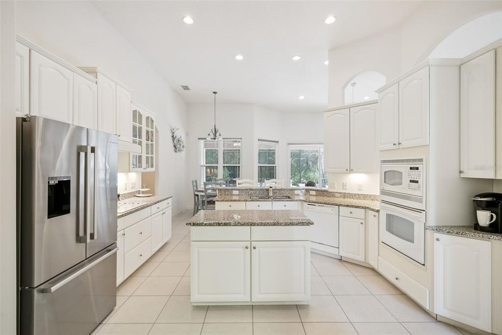 A kitchen with white cabinets, granite countertops, stainless steel appliances, and a central island — 10490 WISCANE AVENUE, ORLANDO, FL