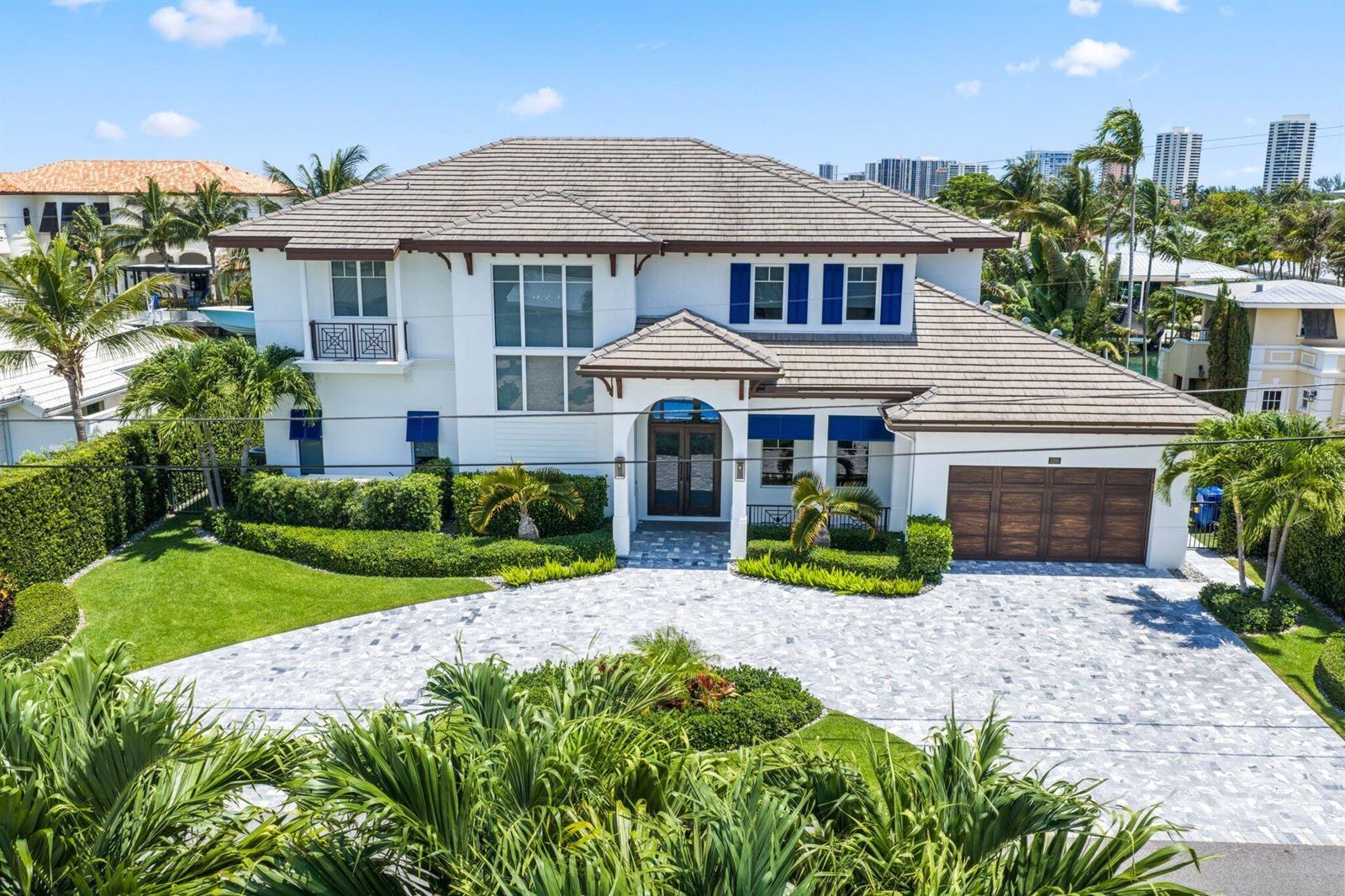 An exterior view of a two-story white house with a tiled roof and paved driveway — 1200 Bimini Lane, Singer Island FL 33404, SINGER ISLAND, FL