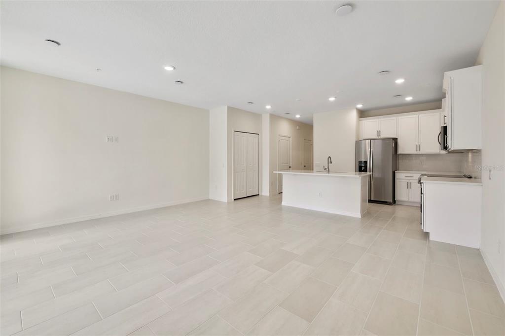 An open-concept kitchen and living area features white cabinetry, stainless steel appliances, and tile flooring — 543 SOUTHERN EDGE WAY, SANFORD, FL