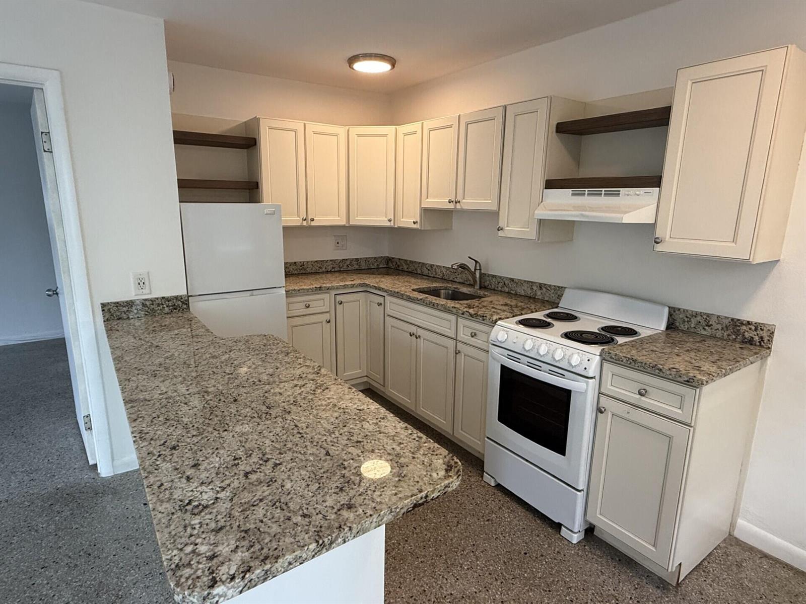 A kitchen featuring off-white cabinets, granite countertops, white appliances, and an open breakfast bar — 1118 N H Street # 4, FL 33460, FL