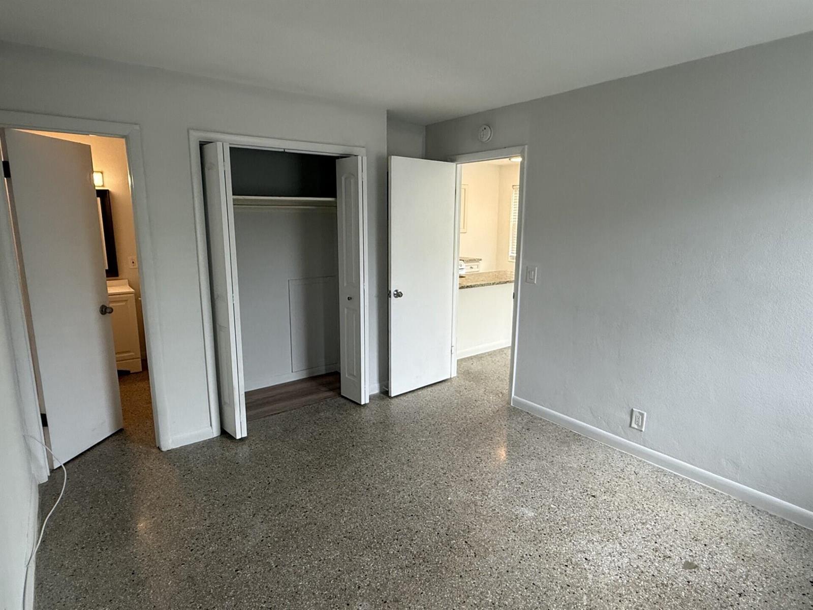 An interior view of a room with gray walls, terrazzo flooring, and three open doorways — 1118 N H Street # 4, FL 33460, FL