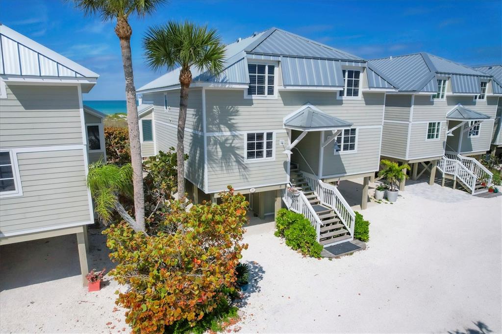 An elevated, light green coastal house with a metal roof sits on a sandy lot — 480 GULF BOULEVARD UNIT 6, BOCA GRANDE, FL