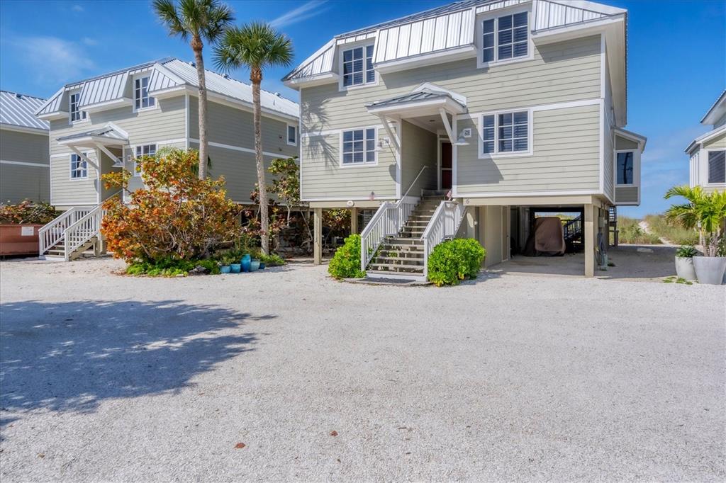 Two elevated, light green houses with metal roofs sit on a gravel lot — 480 GULF BOULEVARD UNIT 6, BOCA GRANDE, FL