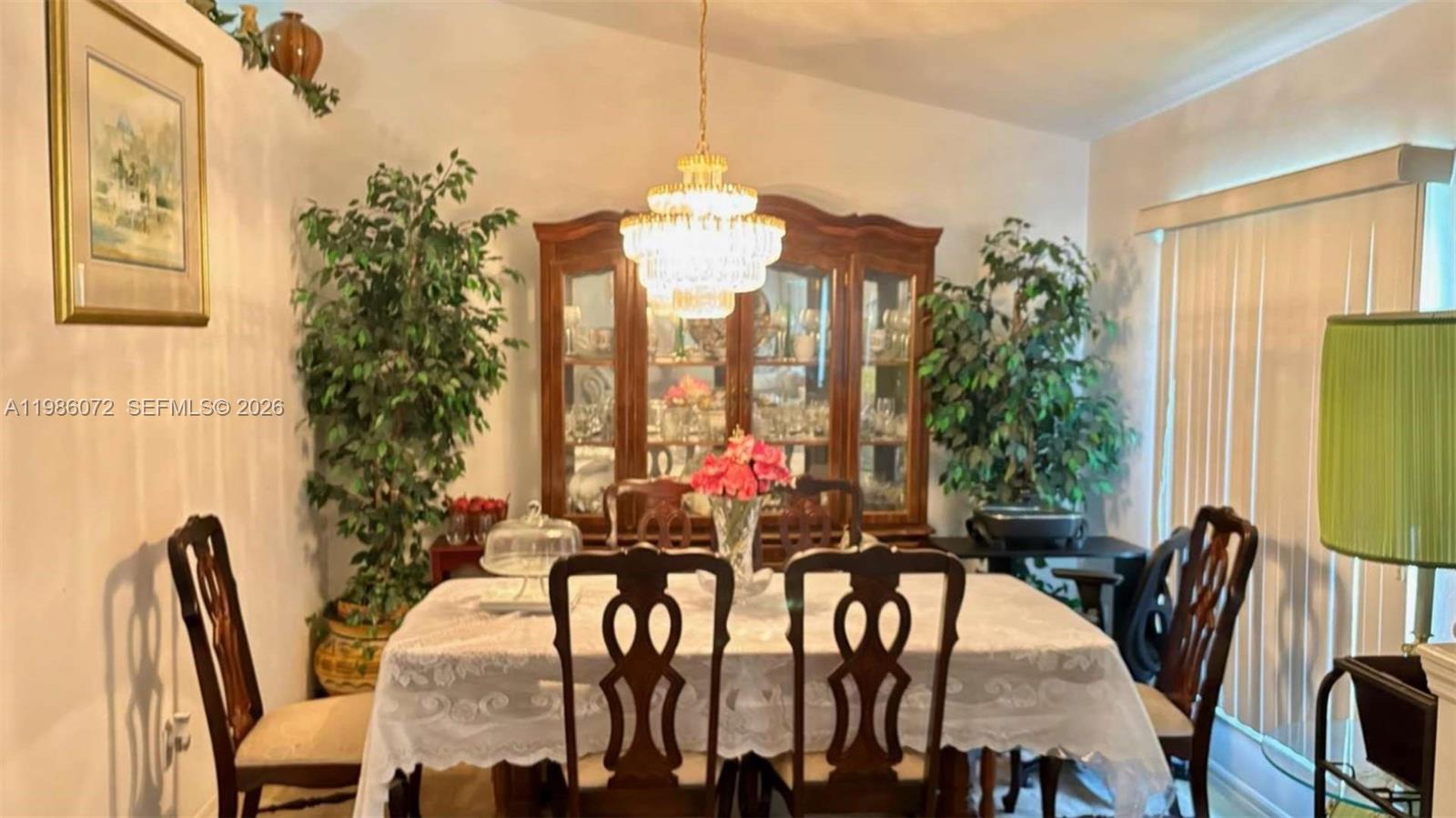 A dining room features a wooden hutch, a crystal chandelier, and a table with chairs — 1122 MCKINLEY AVE, Lehigh Acres FL 33972, LEHIGH ACRES, FL