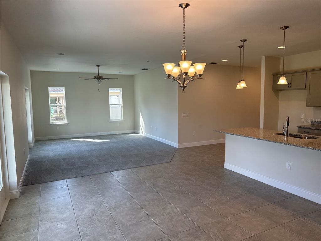 An open-concept living area features gray carpeting, tile flooring, a kitchen island, and pendant lighting — 4420 MIDLAND STREET, NORTH PORT, FL