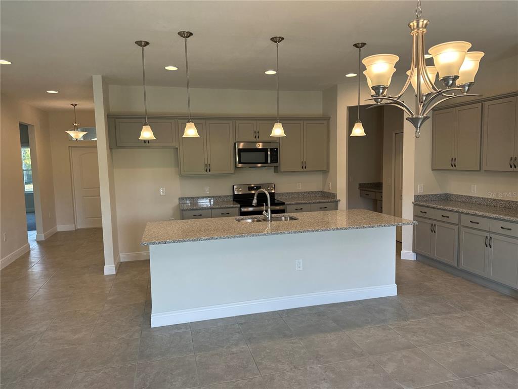 A kitchen features gray cabinets, granite countertops, a center island, and a dining chandelier — 4420 MIDLAND STREET, NORTH PORT, FL