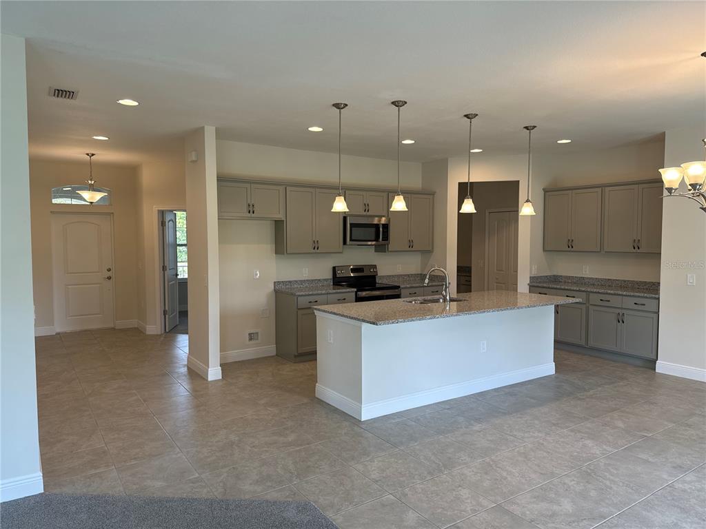 A kitchen features gray cabinets, granite countertops, a central island, and tile flooring — 4420 MIDLAND STREET, NORTH PORT, FL