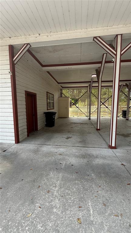 A covered concrete carport features white siding, red trim, and a small storage closet — 1965 SW LITTLE ROAD UNIT D, LAKE CITY, FL