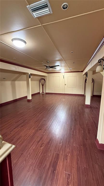 A large, open room features wood-look flooring, a ceiling fan, and decorative wall panels — 1965 SW LITTLE ROAD UNIT D, LAKE CITY, FL