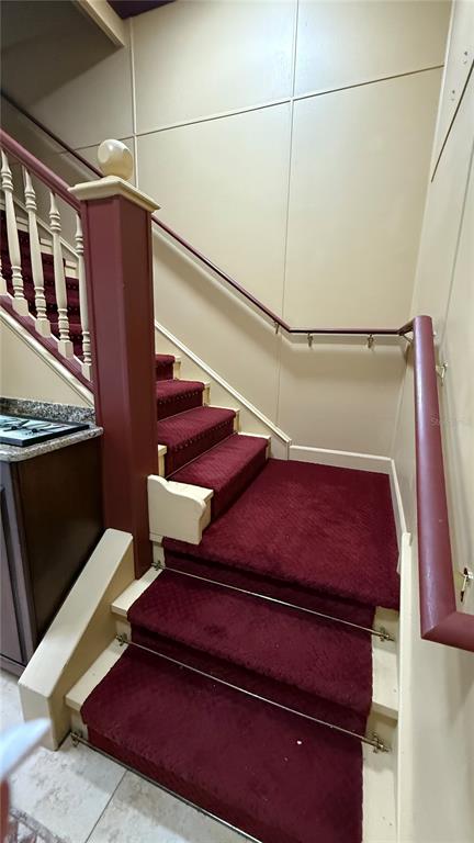 A staircase with red carpet and a wooden railing leads upward against a paneled wall — 1965 SW LITTLE ROAD UNIT D, LAKE CITY, FL