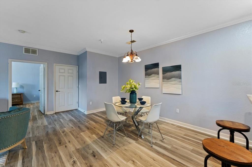 A dining area features a glass-topped table, four white chairs, and wood-look flooring — 1361 TUSCAN TERRACE UNIT 7301, DAVENPORT, FL