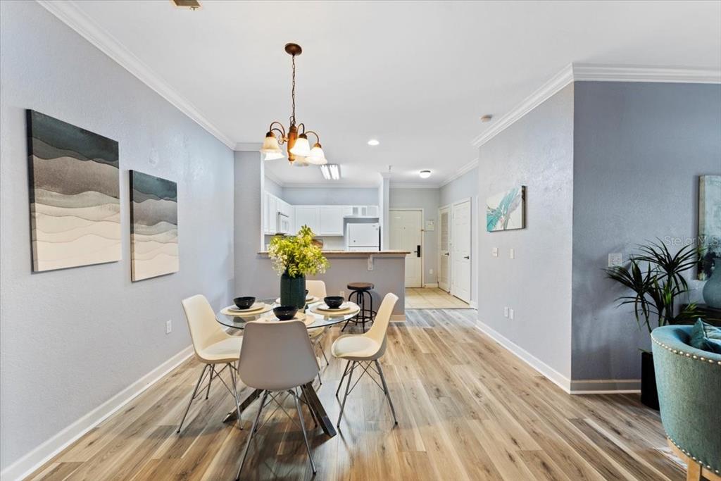 A dining area with a glass table, four chairs, and a chandelier opens to a kitchen — 1361 TUSCAN TERRACE UNIT 7301, DAVENPORT, FL