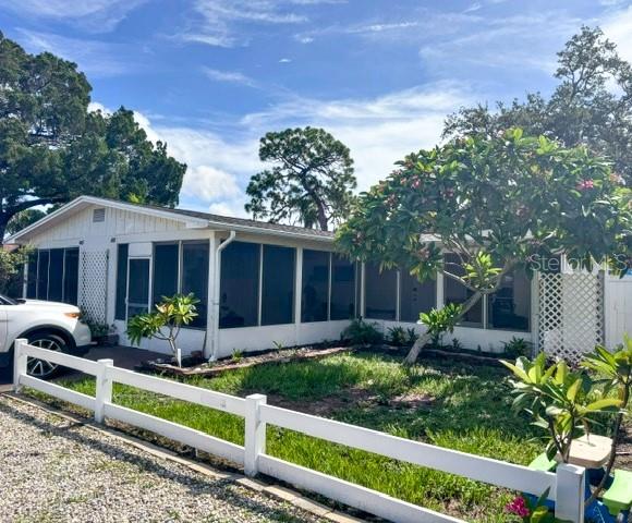 A white single-story house with a screened-in porch and a white fence in the yard — 4805 21ST STREET W, BRADENTON, FL